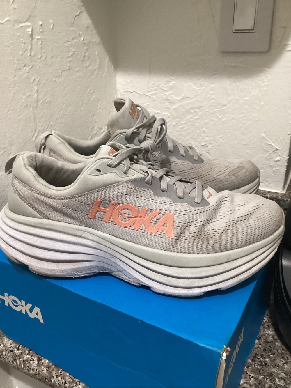 Hoka running shoes in light gray with peach logo